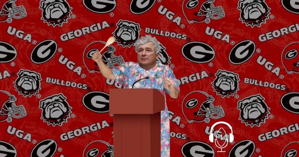 aunt kirby smart in front of a podium with a Georgia Bulldogs background